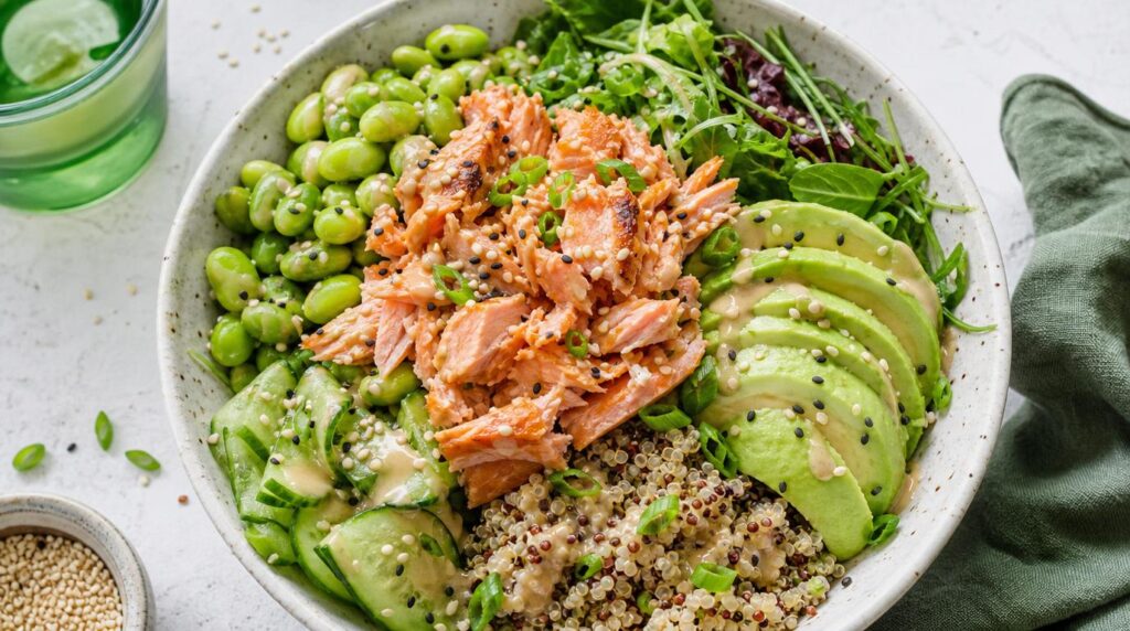 Salmon and Avocado Power Bowl in a bowl with flaked salmon, avocado, greens, edamame and sesame dressing